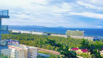 A modern hotel with a glass facade overlooking a coastal area, featuring multiple buildings and a view of the sea.