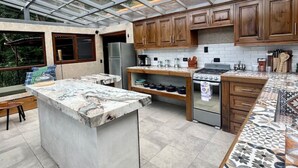 Eine moderne Küche mit einer großen Kochinsel, Holzschränken und einer Glasdecke.