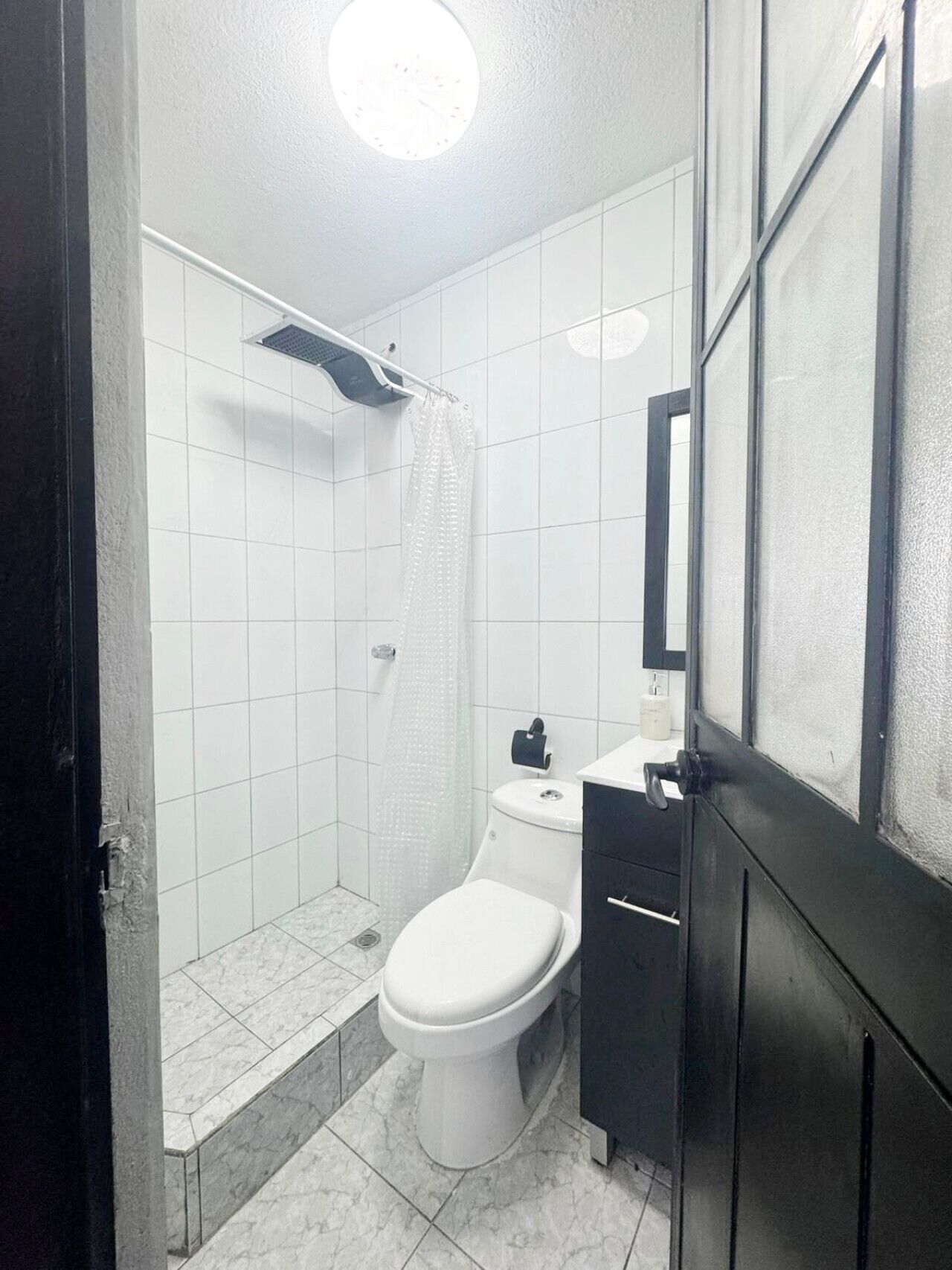 Een kleine, praktische badkamer met toilet, douche en wastafel.