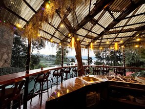 Ulkoterassi, jossa voi ruokailla ja josta avautuu näkymä maaseudulle. Terasseissa on maalaishenkinen metallikatto, puiset pöydät ja tuolit sekä roikkuvat valaisimet.