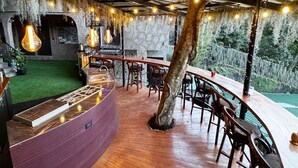 Ein Restaurant im Innenbereich mit einer Holztheke, hängenden Lampen und Blick ins Freie.