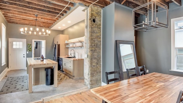 A modern kitchen with a central island, wooden flooring, and exposed brick walls. - Large Milwaukee Home • 4BR • Fast WiFi (Milwaukee)