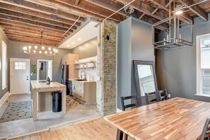 A modern kitchen with a central island, wooden flooring, and exposed brick walls. - Large Milwaukee Home • 4BR • Fast WiFi (Milwaukee)