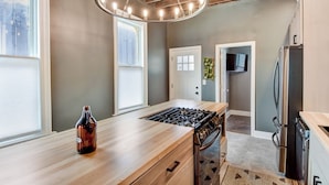 A modern kitchen with a wooden countertop, a gas stove, a built-in oven, and a stainless steel refrigerator. - Large Milwaukee Home • 4BR • Fast WiFi (Milwaukee)