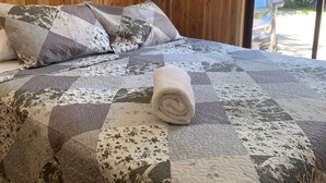A bed with a quilt, pillows, and a rolled towel. - Cabañas El Nativo 2 - Licán Ray (Villarrica)