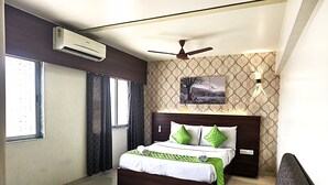 A modern bedroom with a large bed, a ceiling fan, and a window with curtains. - Hotel Express Airoli (Navi Mumbai)