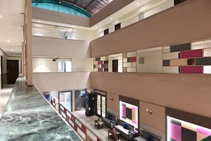 A multi-level hotel lobby with a marble floor, seating areas, and a 'GAYATRI BANQUET' sign. - Hotel Express Airoli (Navi Mumbai)