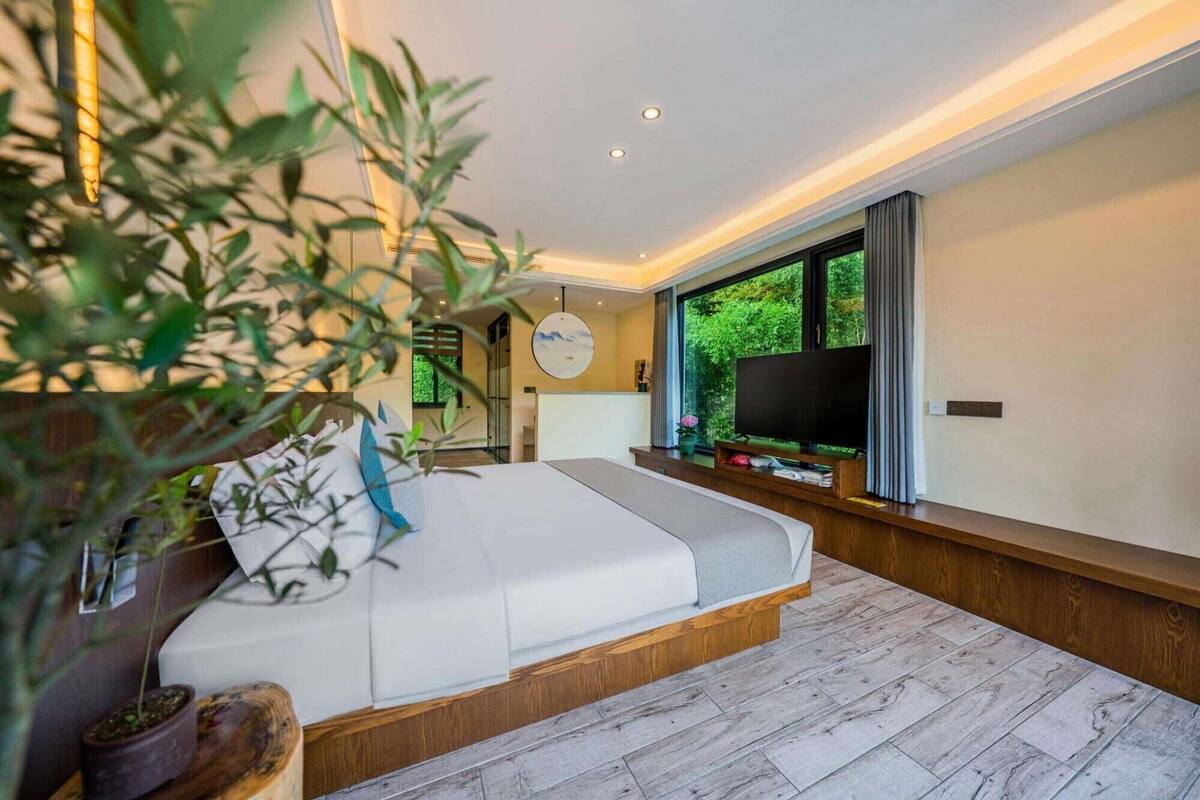 Una camera da letto moderna con un letto grande, una televisione e vista sul verde.