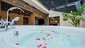 A large indoor hot tub with rose petals floating on the water, a modern faucet, and a view of the sky through a large window. - Shenshan Wild Escape (Huzhou)