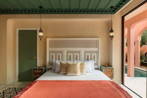 A bedroom with a bed, two nightstands, a decorative headboard, and a view of an outdoor area. - New Moroccan Riad · Private Pool · Aldea Zama (Tulum)
