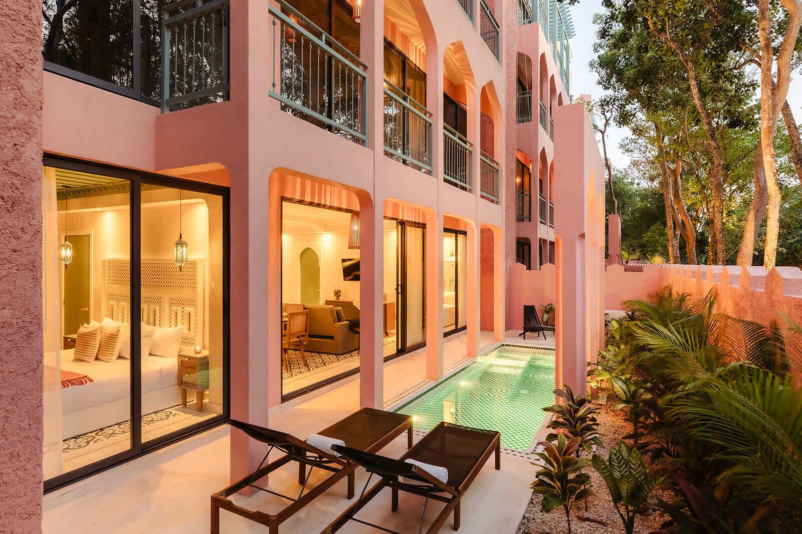 Un edificio de varios pisos con balcones, piscina y mobiliario exterior.