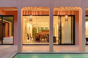 A modern interior with a dining area, kitchen, and a poolside view. - New Moroccan Riad · Private Pool · Aldea Zama (Tulum)