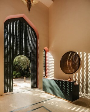 A modern interior with a geometric doorway, a round wall-mounted light, and a minimalist console table. - New Moroccan Riad · Private Pool · Aldea Zama (Tulum)