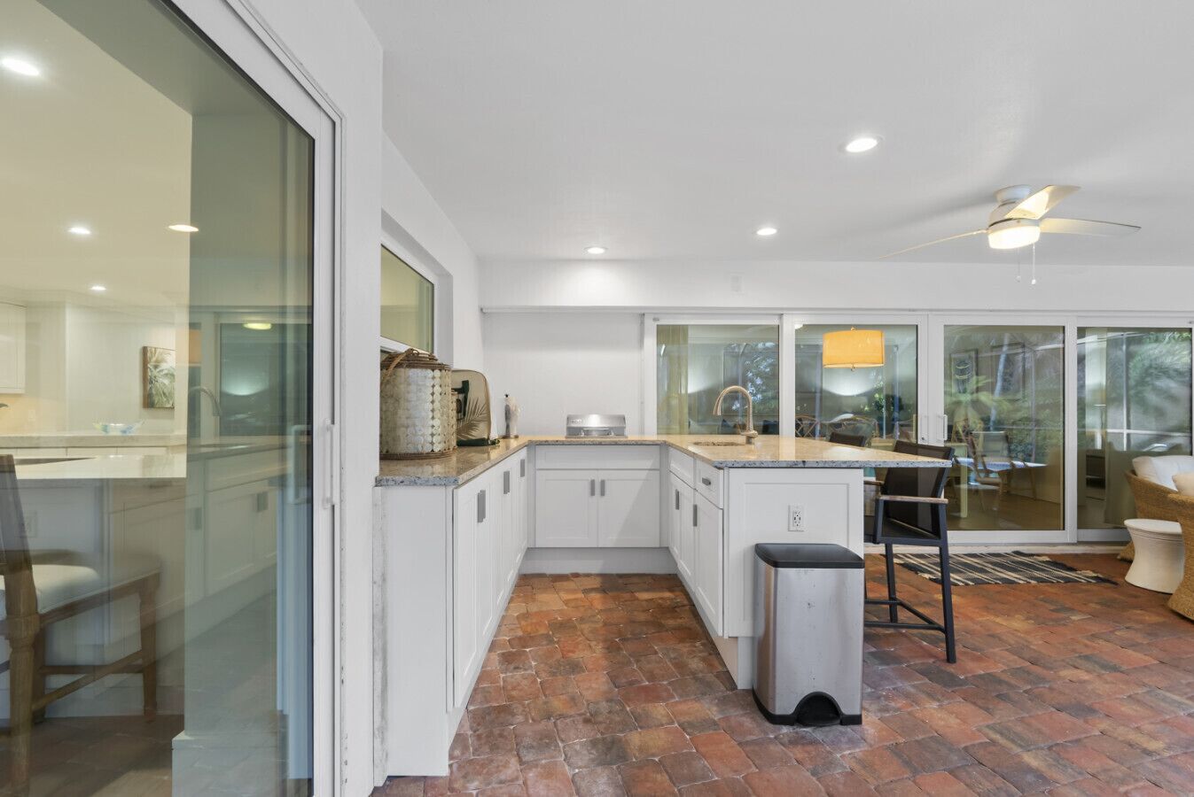 A modern kitchen with white cabinets, a large island, and a dining area with a view.