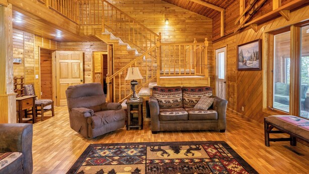 A wooden interior with a staircase, a sofa, a chair, and a rug. - Cedar Point Resort and Campground (Marcell)