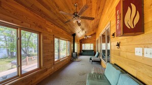A cabin interior with wooden walls, large windows, a ceiling fan, and a fire extinguisher on the wall. - Cedar Point Resort and Campground (Marcell)
