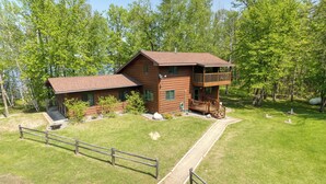 A two-story wooden cabin with a balcony, surrounded by a well-maintained lawn and trees. - Cedar Point Resort and Campground (Marcell)