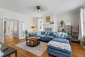 Ein geräumiges Wohnzimmer mit einem blauen Ecksofa, einem Couchtisch und einem Kamin.