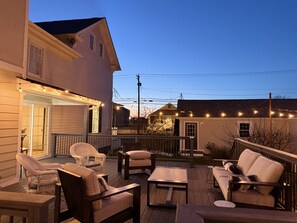 Eine Terrasse mit Gartenmöbeln, darunter Stühle und Tische, und ein Haus im Hintergrund.