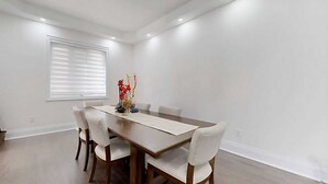A dining area with a rectangular table, six chairs, a vase with flowers, and recessed ceiling lights. - A cozy getaway for a quiet relaxing spell. (Vaughan)