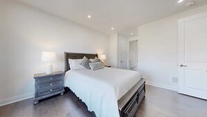 A bedroom with a bed, nightstands, and a dresser. There is a door to the right and a closet to the left. - A cozy getaway for a quiet relaxing spell. (Vaughan)