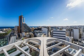 A high-rise building with a modern architectural design, featuring a prominent tower and multiple balconies. - Official Mercury Suites With Rooftop Pool Access (St. Julian's)