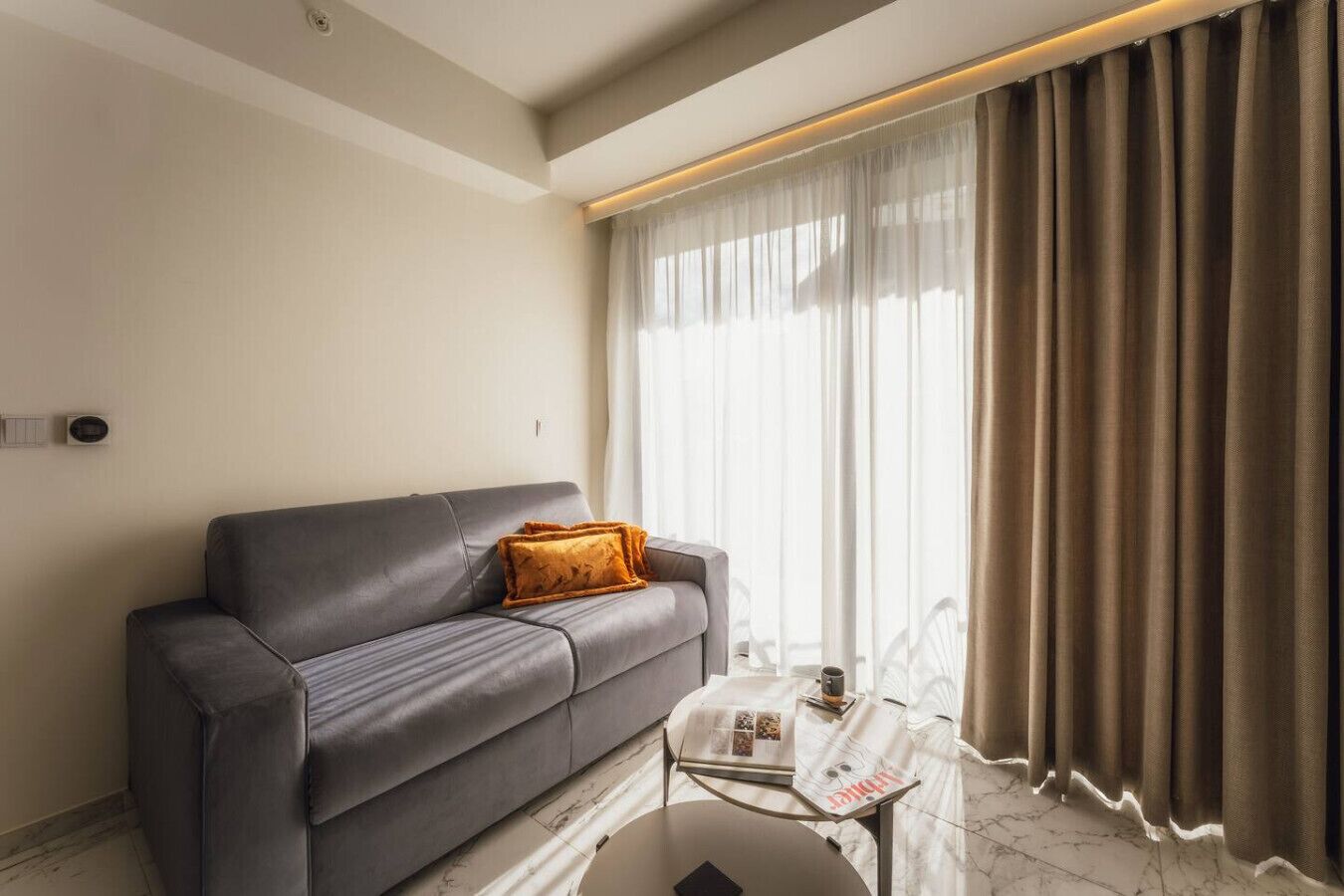 Een moderne woonkamer met een grijze bank, een klein bijzettafeltje en een tijdschrift.
