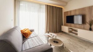 Ein modernes Wohnzimmer mit einem grauen Sofa, einem kleinen runden Tisch und einem an einer Holzwand montierten Fernseher.