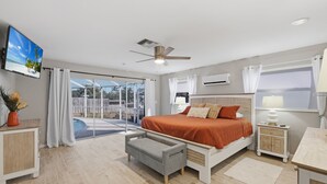 Een moderne slaapkamer met een bed, een bureau, een stoel, een plafondventilator en uitzicht op de omgeving.