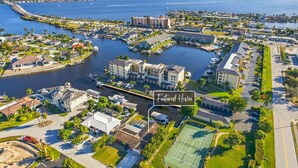 Luchtbeeld van een kustgebied met woonhuizen en een jachthaven, met een groot gebouw dat 'Featured Home' vermeldt.