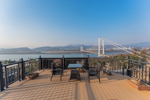 A deck with a table and chairs overlooking a body of water and a bridge. - Shiyunjian Homestay  (Yichang)