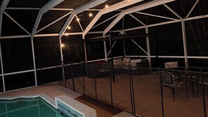 A covered outdoor swimming pool area with a patio and seating.