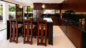 Une cuisine moderne avec des meubles en bois foncé, un îlot central et des luminaires suspendus.