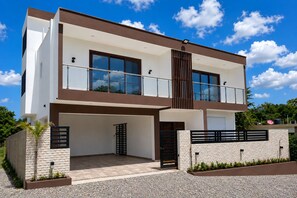 A modern two-story house with a balcony, a garage, and a stone facade.