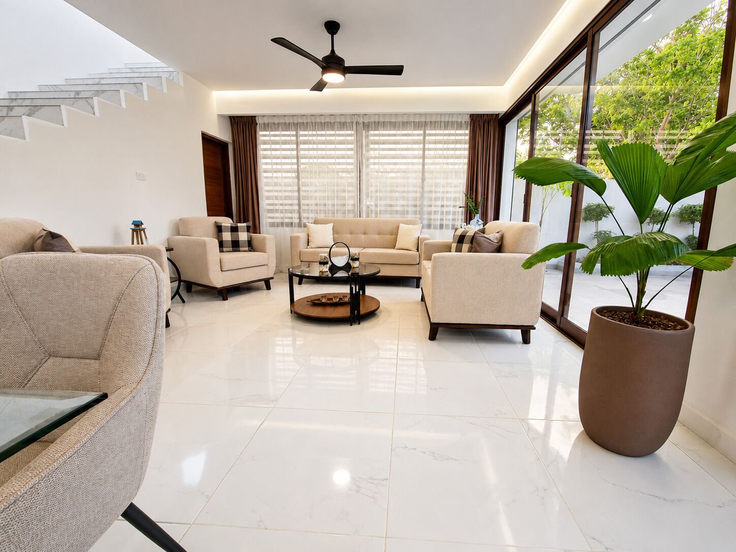 A modern living room with a sofa set, a coffee table, and a large potted plant.