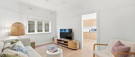 Un salon moderne avec un canapé, une table basse et un téléviseur.