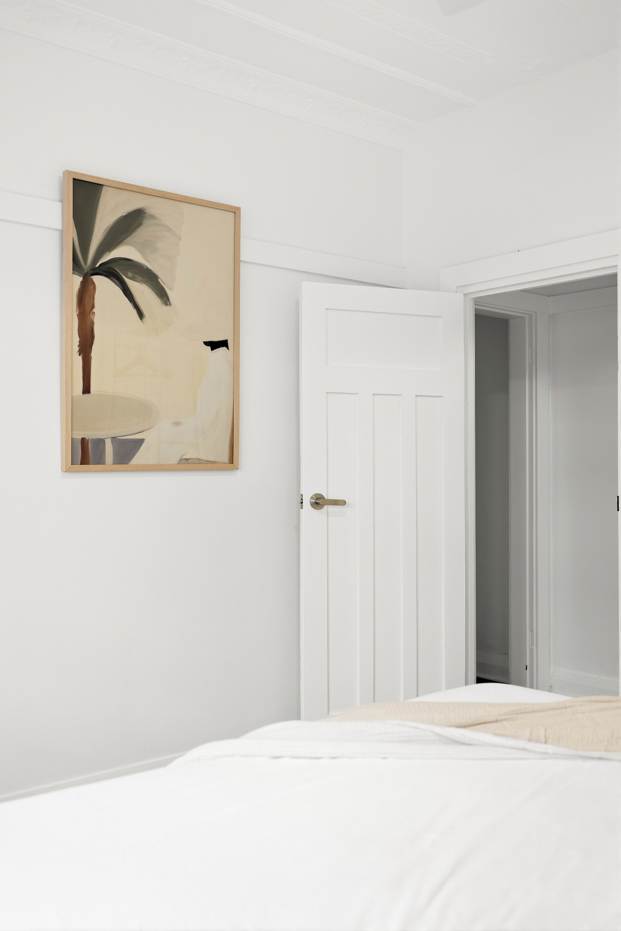 Un dormitorio con una cama, una puerta y una obra de arte enmarcada en la pared.