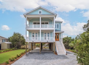 A two-story house with a balcony on the upper floor, a front door, and a staircase leading to the entrance.