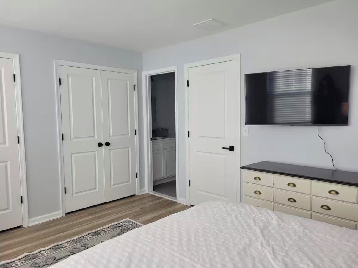 A bedroom with a bed, a dresser, a television, and a closet.