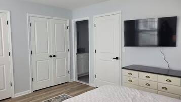 A bedroom with a bed, a dresser, a television, and a closet.