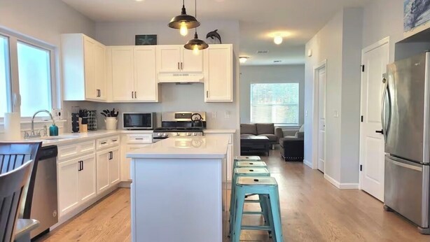 Una cocina moderna con armarios blancos, una isla central y un refrigerador de acero inoxidable.