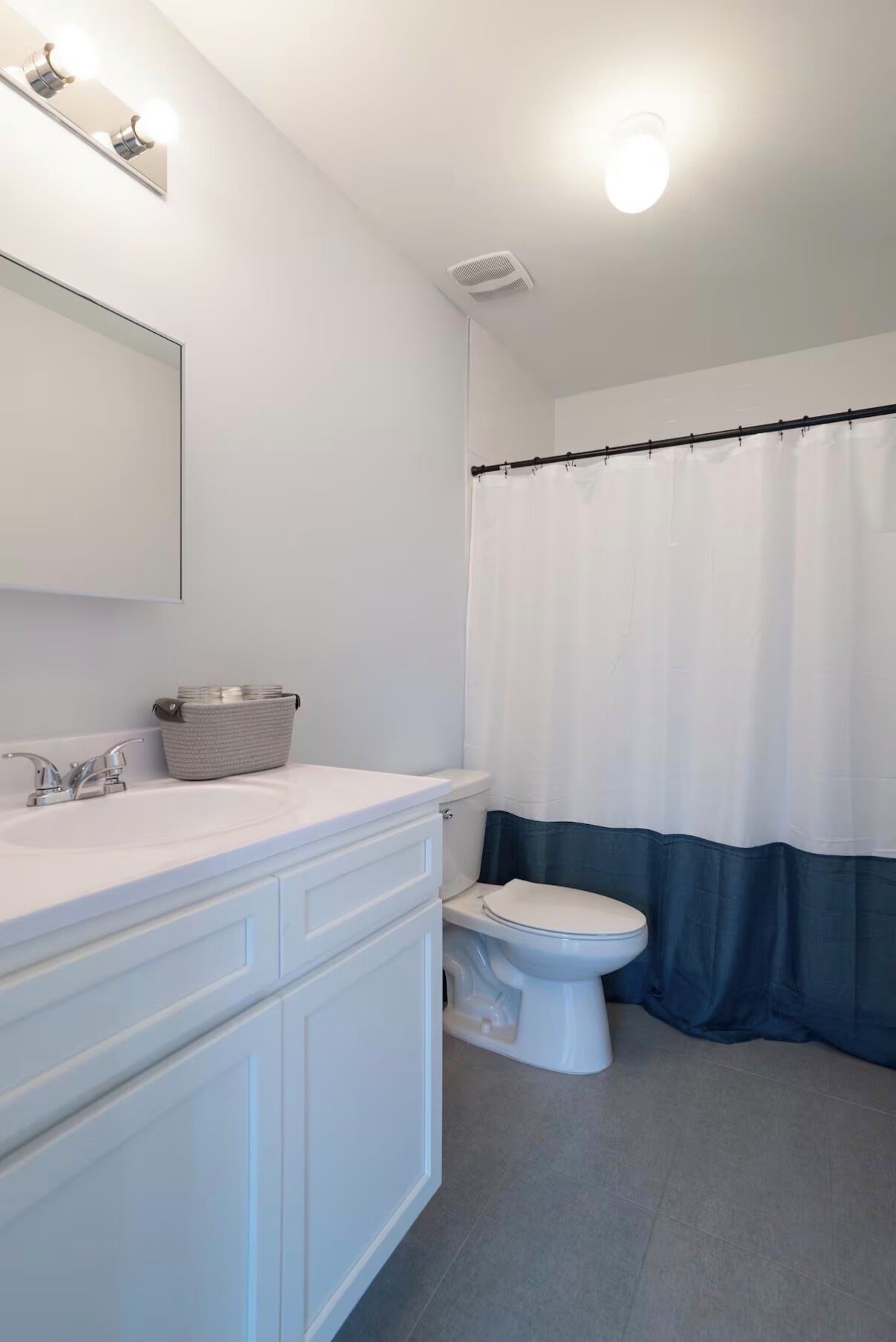 Une salle de bain avec un lavabo blanc, des toilettes et un rideau de douche.