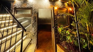 A stone staircase leading to a door with a glass panel, surrounded by lush greenery and a small water feature. - Guatemala Dreams Grand Chalet (San Lucas Tolimán)