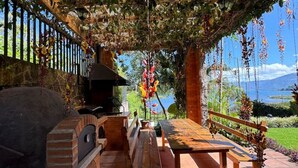 An outdoor patio with a brick barbecue, wooden benches, and a pergola covered in vines. - Guatemala Dreams Grand Chalet (San Lucas Tolimán)