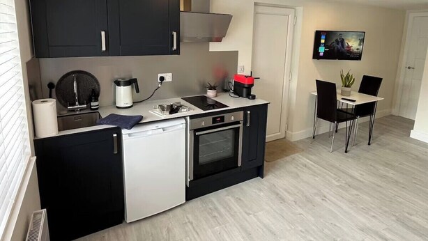 Eine kompakte Küche mit Geschirrspüler, Backofen und einer kleinen Essecke mit Tisch und Stühlen.