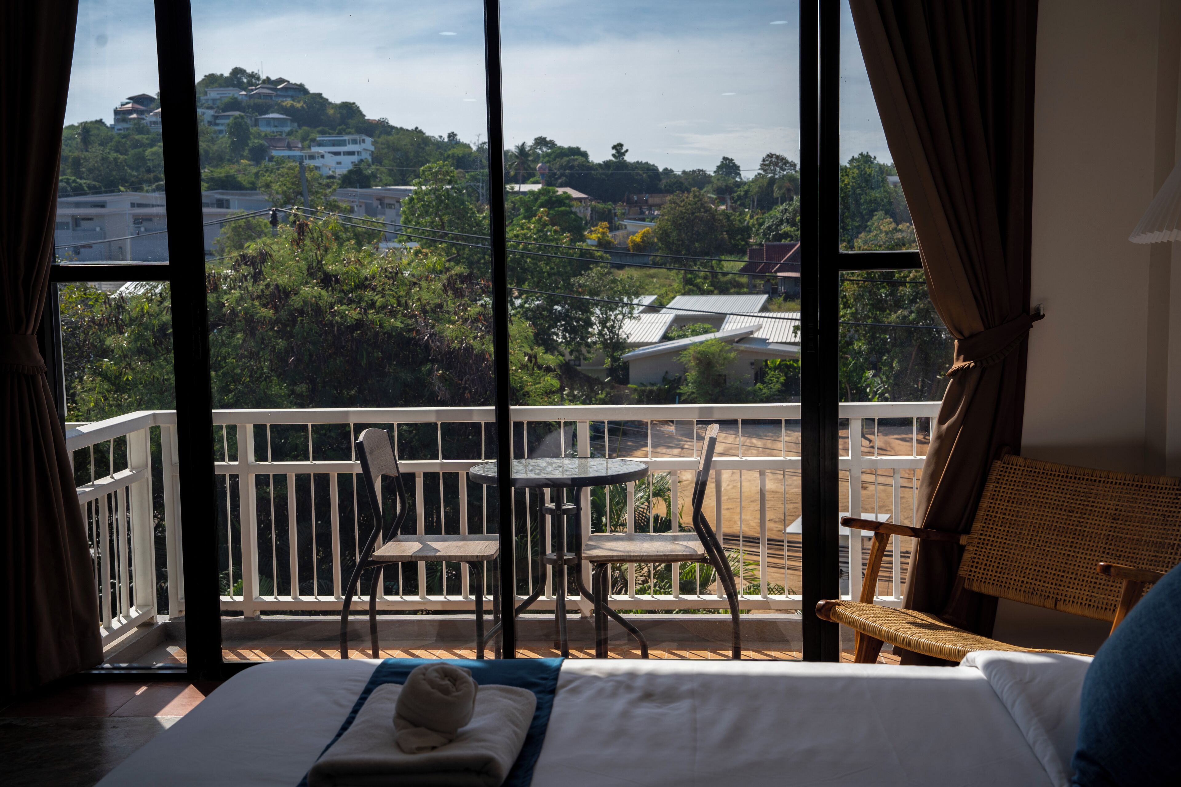 Quarto de hotel com varanda, uma cama, uma mesa e cadeiras.