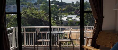 A hotel room with a balcony, a bed, a table, and chairs.
