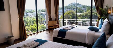 A hotel room with two beds, a view of the city, and a balcony.