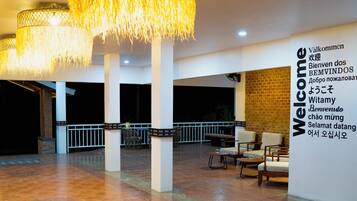 A spacious lobby with a tiled floor, a reception desk, and a wall with a multilingual welcome sign.