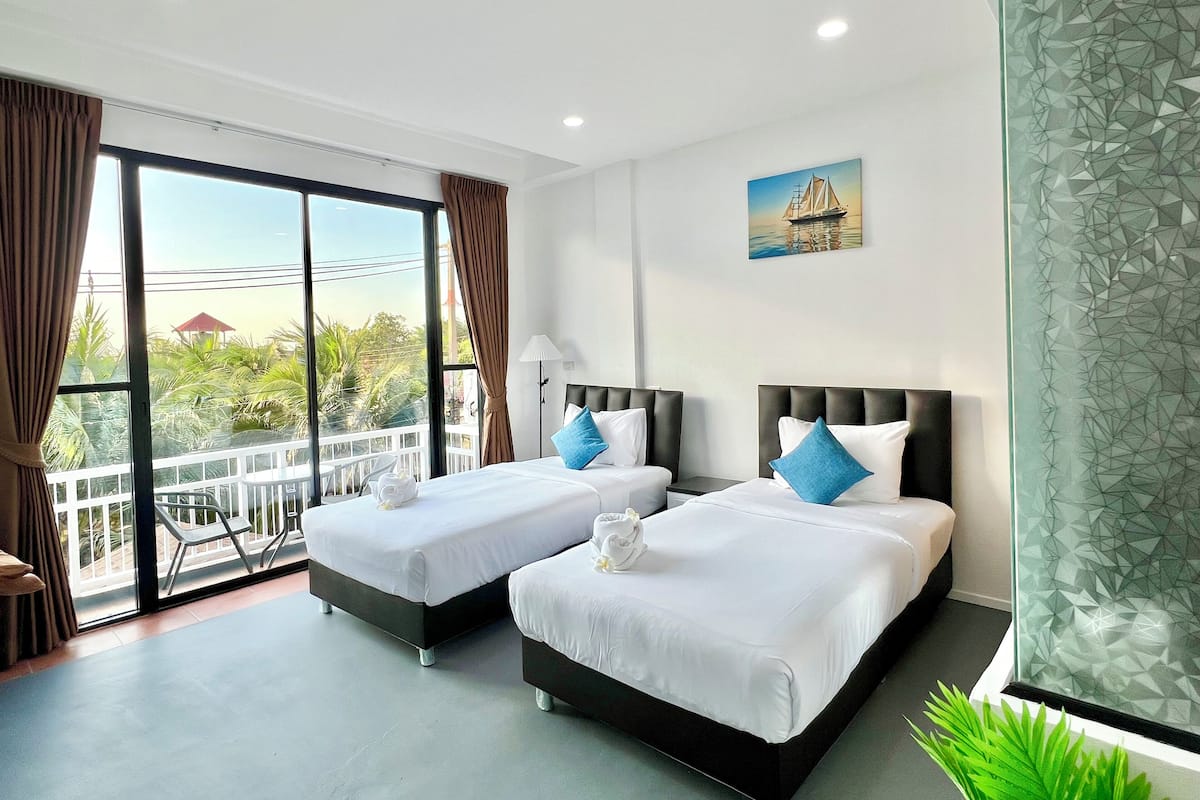 Habitación con 2 camas individuales, balcón, vista al jardín | Espacio para trabajar con laptop y tabla de planchar con plancha